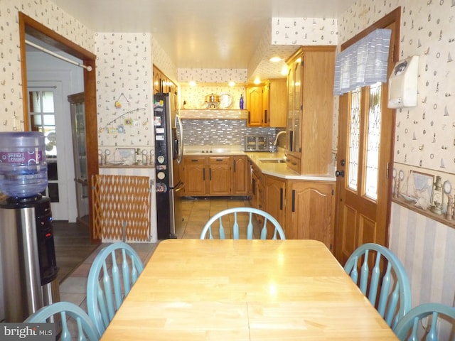 kitchen featuring decorative backsplash, light tile patterned floors, stainless steel refrigerator, and sink