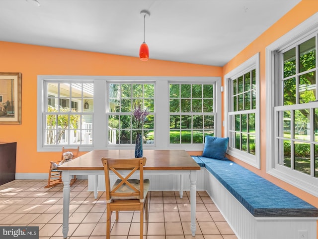 sunroom featuring breakfast area, vaulted ceiling, and plenty of natural light