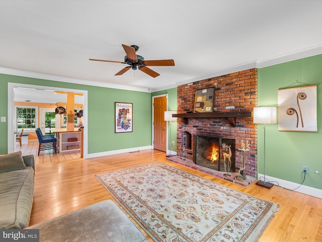 living room with hardwood / wood-style floors, ceiling fan, ornamental molding, and a brick fireplace