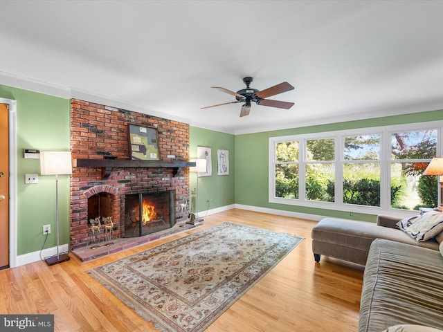 living room featuring hardwood / wood-style flooring, a brick fireplace, ceiling fan, and ornamental molding