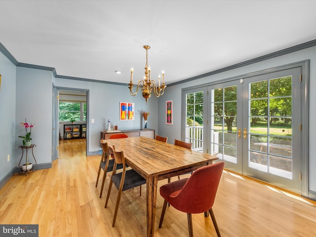 dining space with a chandelier, light wood-type flooring, ornamental molding, and french doors