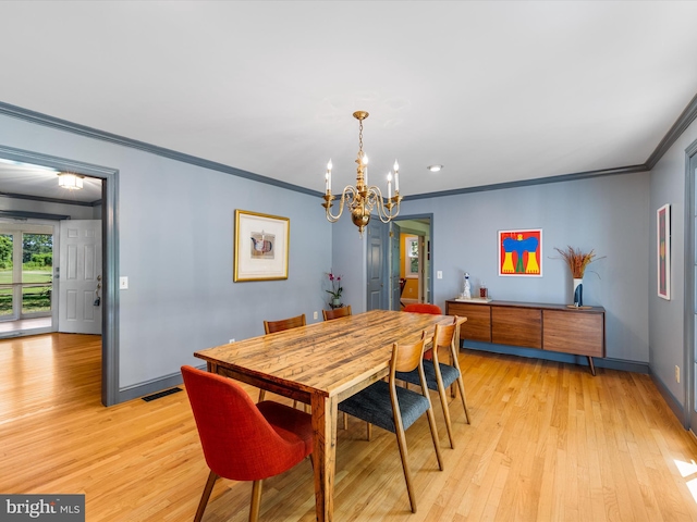 dining area with crown molding, a chandelier, and light wood-type flooring