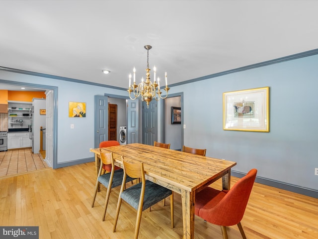 dining room with light hardwood / wood-style floors, crown molding, washer / clothes dryer, and a chandelier