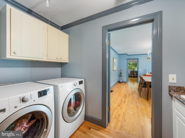 laundry area featuring washer and dryer, light wood-type flooring, cabinets, and ornamental molding