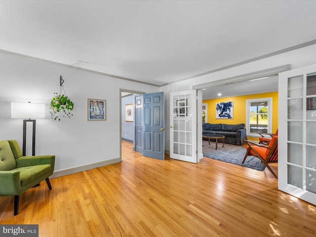 living area with light hardwood / wood-style flooring and ornamental molding