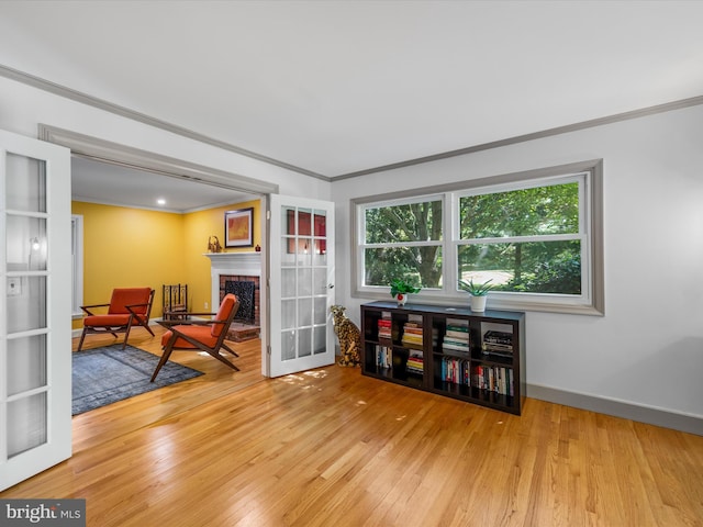 sitting room with a fireplace, ornamental molding, and light wood-type flooring