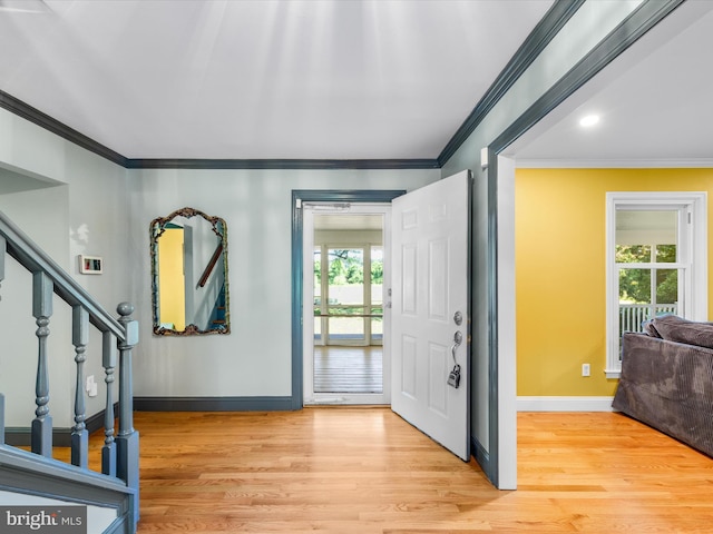 foyer entrance with light wood-type flooring and crown molding