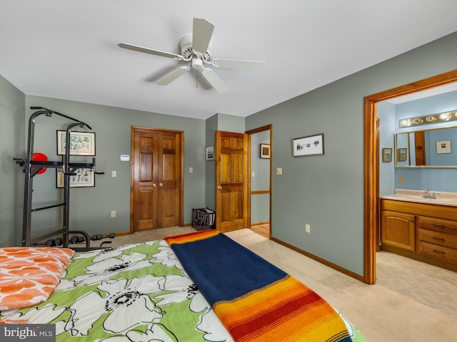 bedroom with ensuite bathroom, sink, ceiling fan, light colored carpet, and a closet