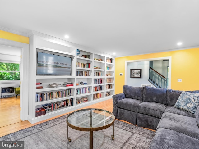 living room featuring hardwood / wood-style floors, built in shelves, and crown molding