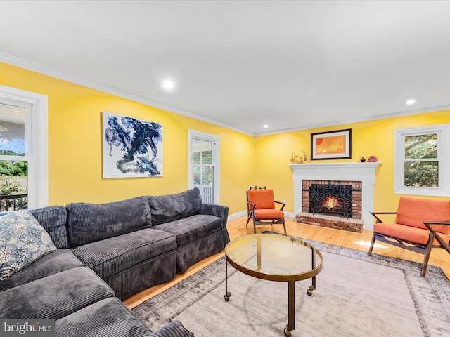 living room with a fireplace, plenty of natural light, ornamental molding, and hardwood / wood-style flooring