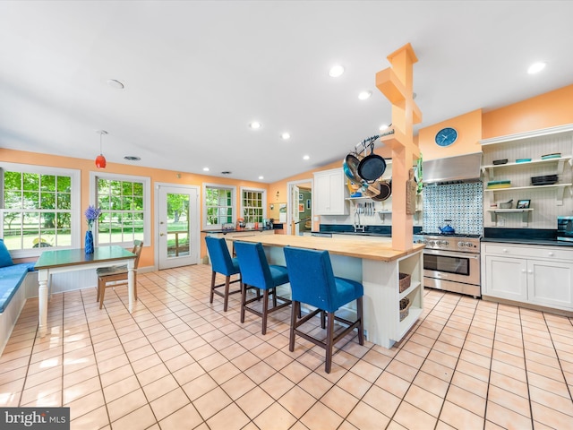 kitchen with butcher block countertops, stainless steel range, white cabinets, and a center island