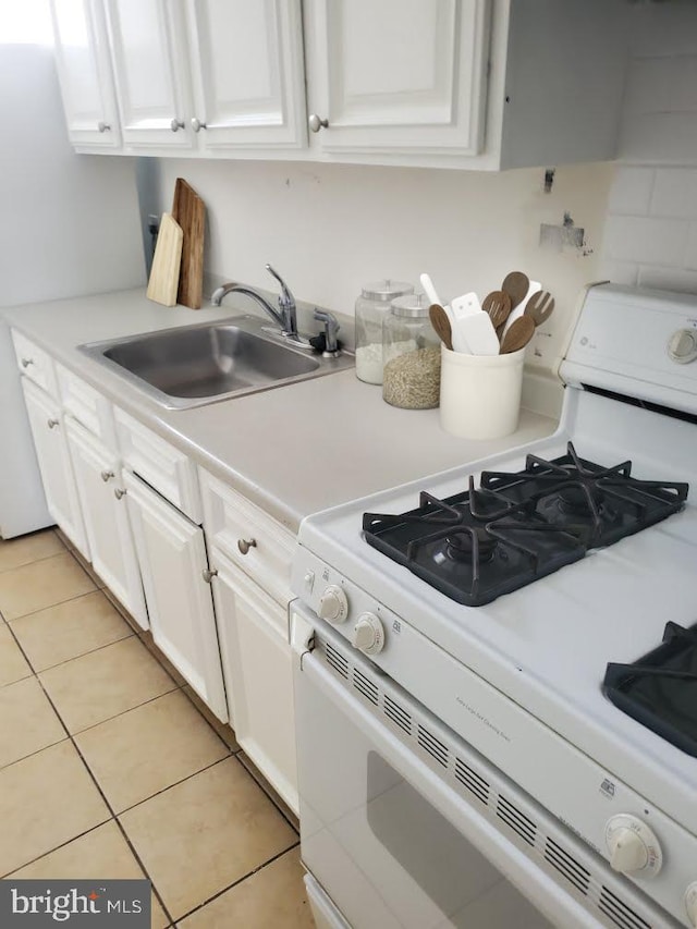 kitchen featuring white gas range, white cabinetry, sink, and light tile patterned floors