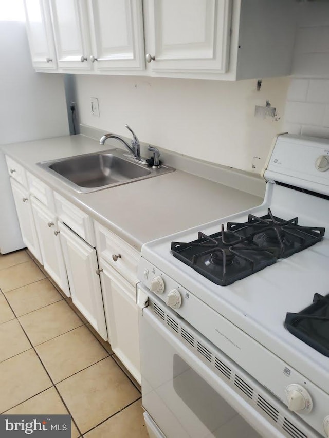 kitchen with white cabinets, light tile patterned flooring, white gas range, and sink