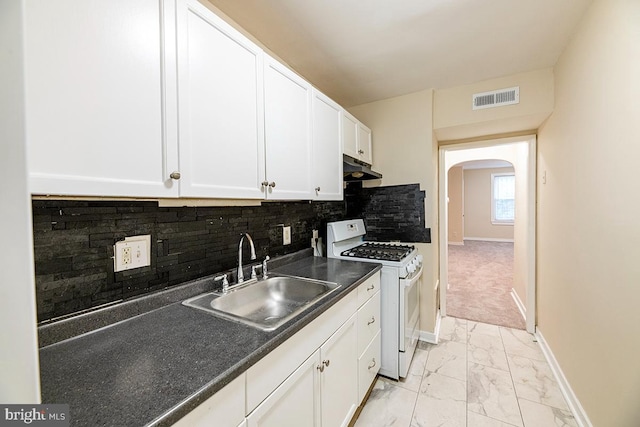 kitchen featuring white cabinets, decorative backsplash, white gas stove, and sink