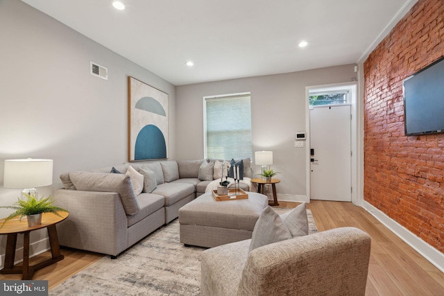 living room featuring light wood-type flooring and brick wall