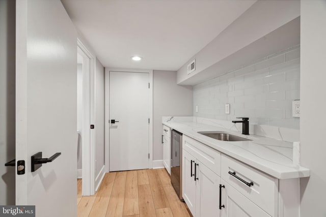 bar featuring light hardwood / wood-style flooring, dishwasher, light stone counters, sink, and white cabinets