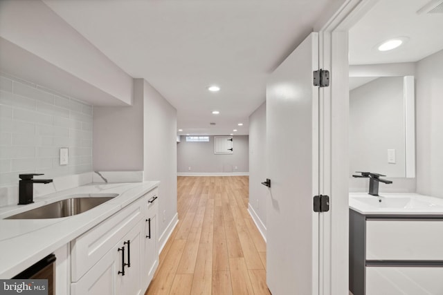 interior space with light stone countertops, sink, white cabinets, and light hardwood / wood-style floors