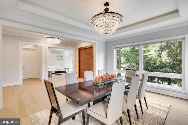 dining room featuring a raised ceiling, light hardwood / wood-style floors, a healthy amount of sunlight, and an inviting chandelier