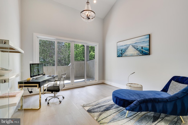 office with hardwood / wood-style floors, high vaulted ceiling, and a notable chandelier