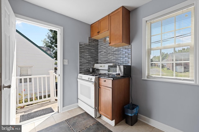 kitchen featuring light tile patterned floors, tasteful backsplash, and gas range gas stove