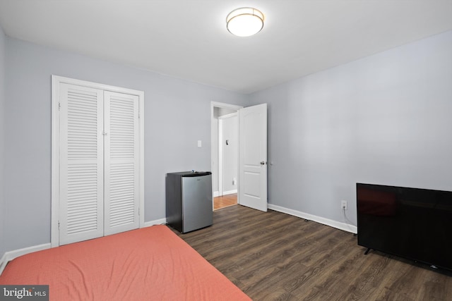 bedroom with stainless steel refrigerator, a closet, and dark hardwood / wood-style floors