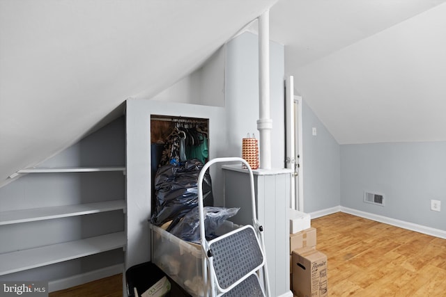 bonus room featuring hardwood / wood-style floors, built in features, and vaulted ceiling