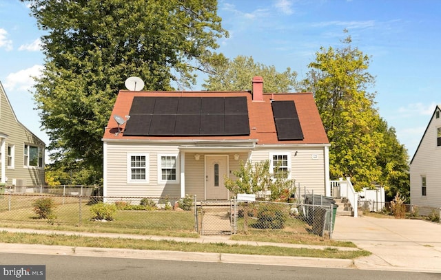 view of front of home with a fenced front yard, roof mounted solar panels, a chimney, and a gate