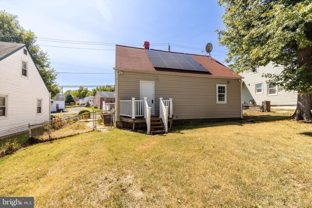 rear view of house with a lawn and solar panels