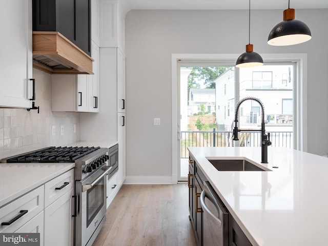 kitchen with appliances with stainless steel finishes, sink, white cabinetry, and decorative light fixtures