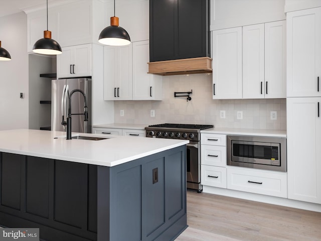 kitchen with pendant lighting, white cabinets, stainless steel appliances, tasteful backsplash, and a kitchen island with sink