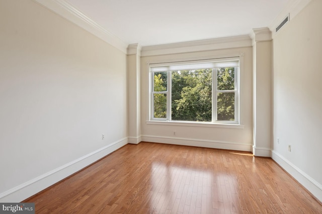 empty room with ornamental molding and light wood-type flooring