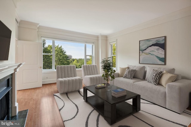 living room with light hardwood / wood-style flooring, a fireplace, and ornamental molding