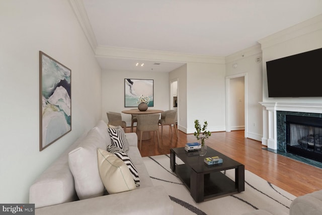 living room with hardwood / wood-style flooring, ornamental molding, and a premium fireplace