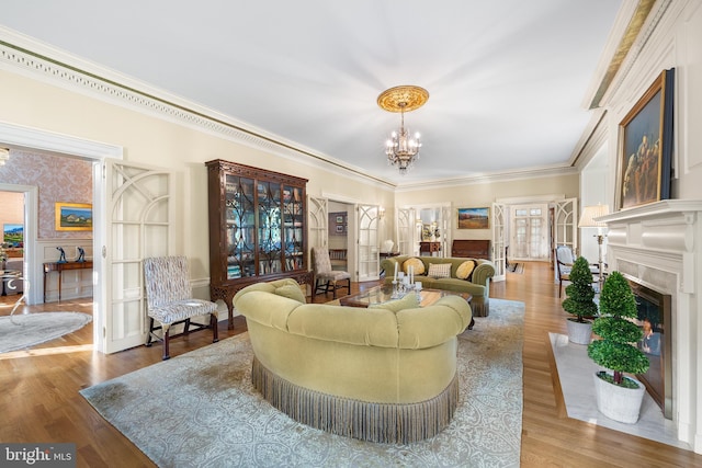 living room featuring crown molding, wood-type flooring, a high end fireplace, and a chandelier