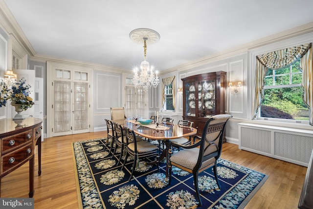 dining area featuring radiator, crown molding, wood-type flooring, and a notable chandelier