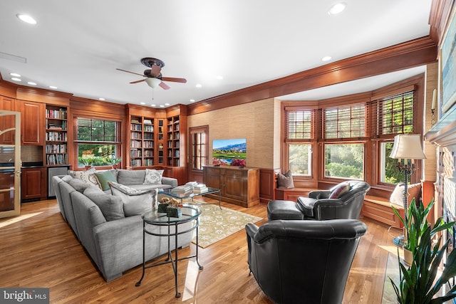 living room with crown molding, ceiling fan, and light wood-type flooring