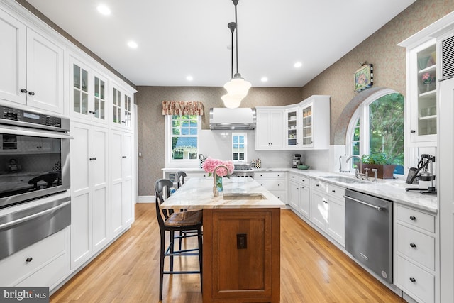 kitchen with a kitchen island, decorative light fixtures, sink, stainless steel appliances, and light stone countertops