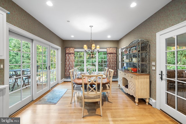 dining area with a baseboard heating unit, a notable chandelier, and light hardwood / wood-style flooring