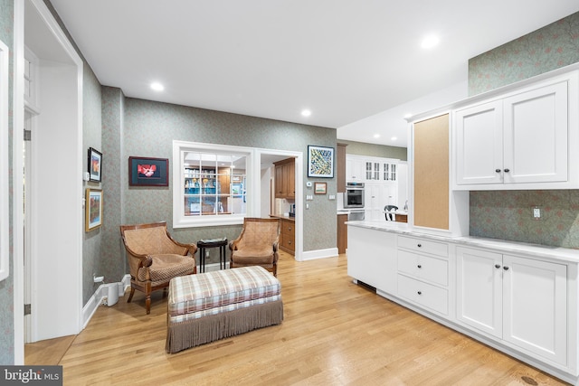 kitchen with white cabinetry, backsplash, and light hardwood / wood-style flooring