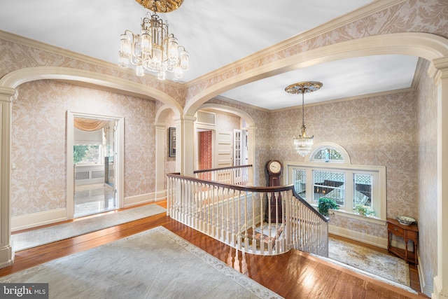 hall with a notable chandelier, crown molding, and wood-type flooring