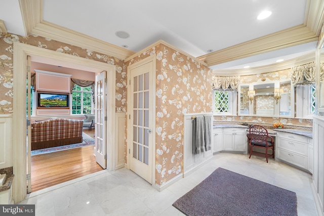 interior space with built in desk, ornamental molding, and white cabinets