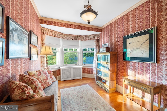 sitting room with radiator, crown molding, and light wood-type flooring