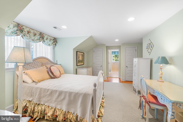 bedroom featuring ensuite bathroom, multiple windows, and light wood-type flooring