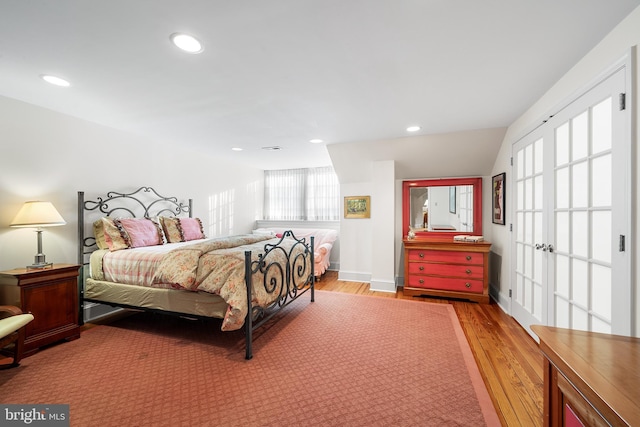 bedroom featuring multiple windows, vaulted ceiling, and light wood-type flooring