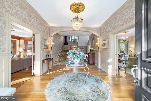 entryway featuring a notable chandelier, crown molding, and light hardwood / wood-style flooring