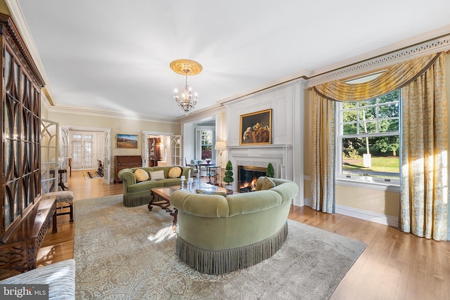 living room featuring an inviting chandelier, ornamental molding, and light hardwood / wood-style floors