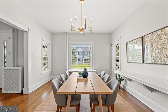 dining area with hardwood / wood-style floors and a notable chandelier