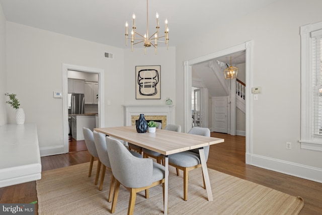 dining area with plenty of natural light, dark hardwood / wood-style flooring, and an inviting chandelier