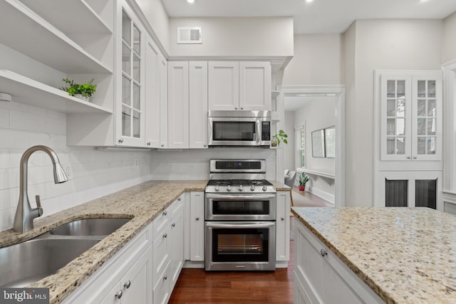 kitchen with white cabinetry, sink, light stone counters, backsplash, and appliances with stainless steel finishes