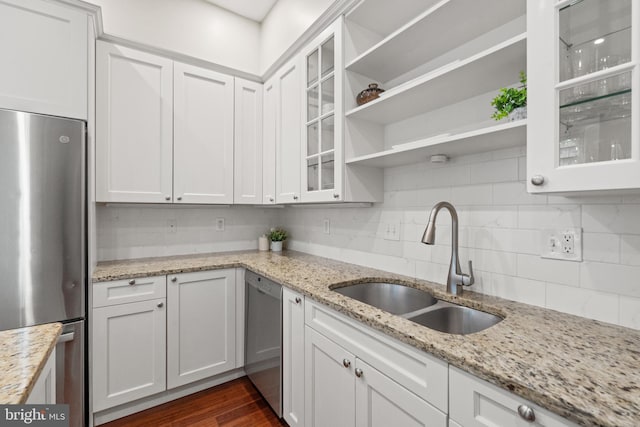 kitchen with appliances with stainless steel finishes, tasteful backsplash, light stone counters, sink, and white cabinetry